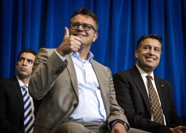 Dag Reckhorn, center, global vice president for Faraday Future, gives a thumps up while sitting with Gov. Brian Sandoval during the  company‘s announcement   at the Sawyer Building onThursda ...