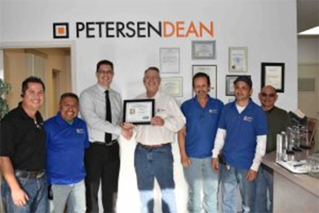 Todd Schultz, chief administrator for the Safety Consultation and Training Section, presents Steve Howard, senior vice president Las Vegas, and the PetersenDean Team with Safe Partner Award. (Cour ...