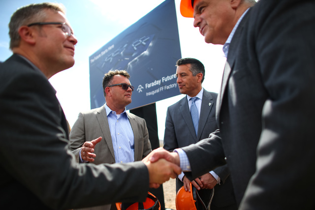 Faraday Future Vice President of Manufacturing Dag Reckhorn, center left, and Gov. Brian Sandoval speak following the groundbreaking for the planned 900-acre manufacturing site in North Las Vegas  ...
