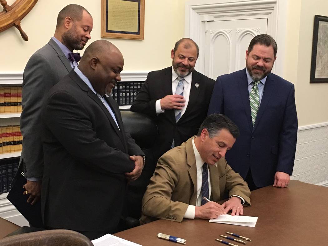 Gov. Brian Sandoval signs into law a bipartisan bill May 8, ensuring the continued reorganization of the Clark County School District, begun in the 2015 session. Attending the ceremony in Carson C ...