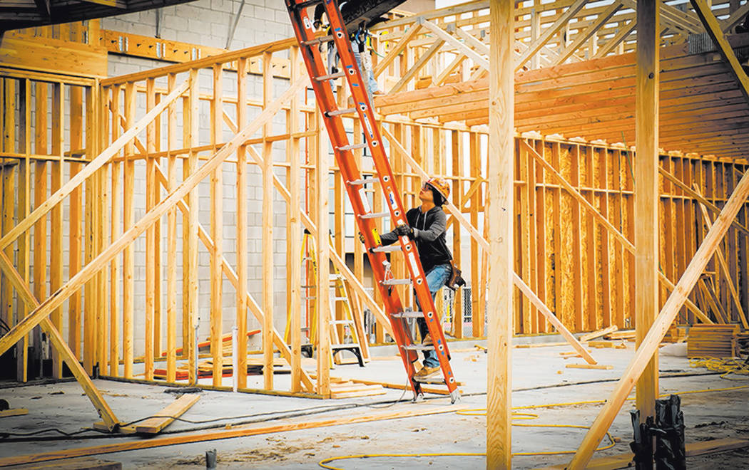 A worker climbs a ladder at a new-home construction site. Valley homebuilders say prices will c ...