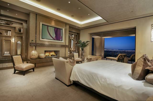 The master bedroom, which opens to a patio, has a large setting area and fireplace. The bed's h ...