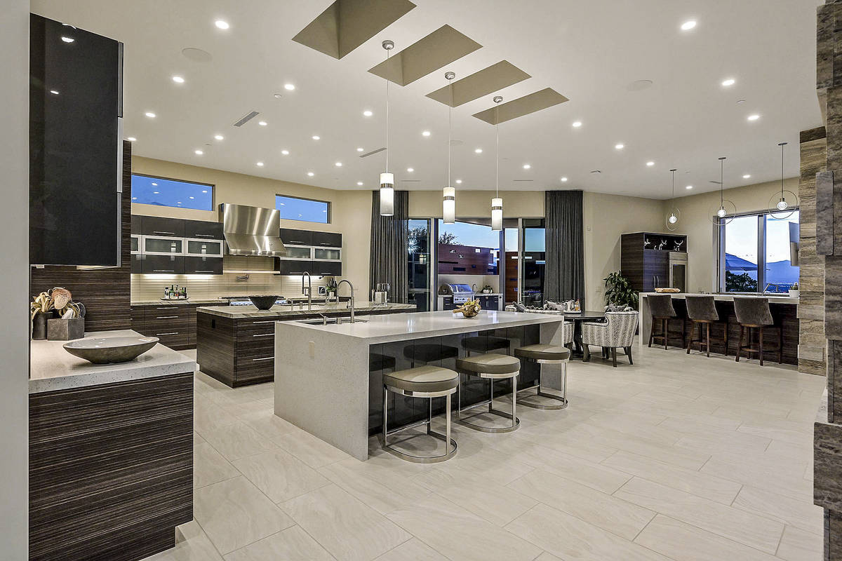 The kitchen features plenty of custom cabinets, Brazilian quartzite waterfall counters and a la ...