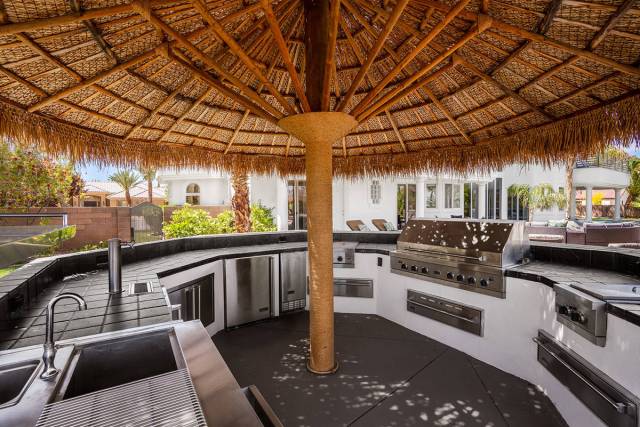 The outdoor kitchen features full round bar seating shaded by a large palapa umbrella. (Michael ...