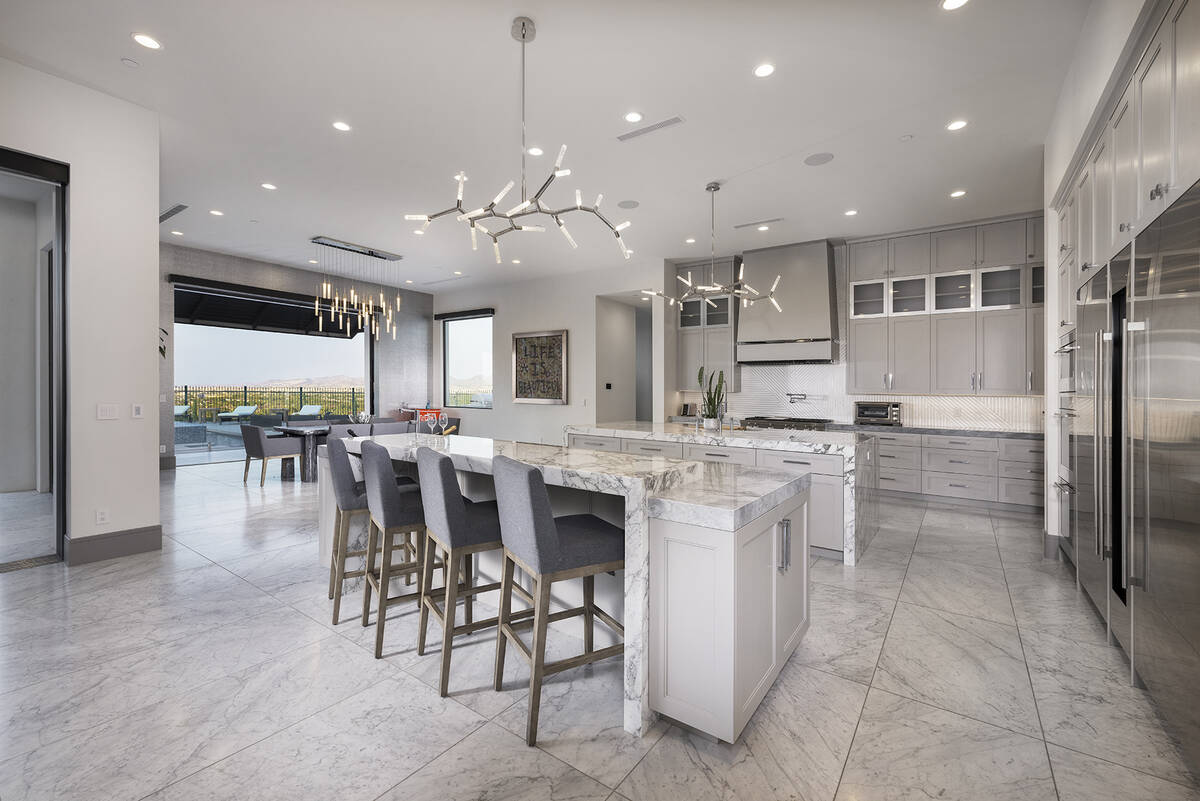 Adjacent to the great room, the kitchen is graced with premium finishes such as custom gray oak ...