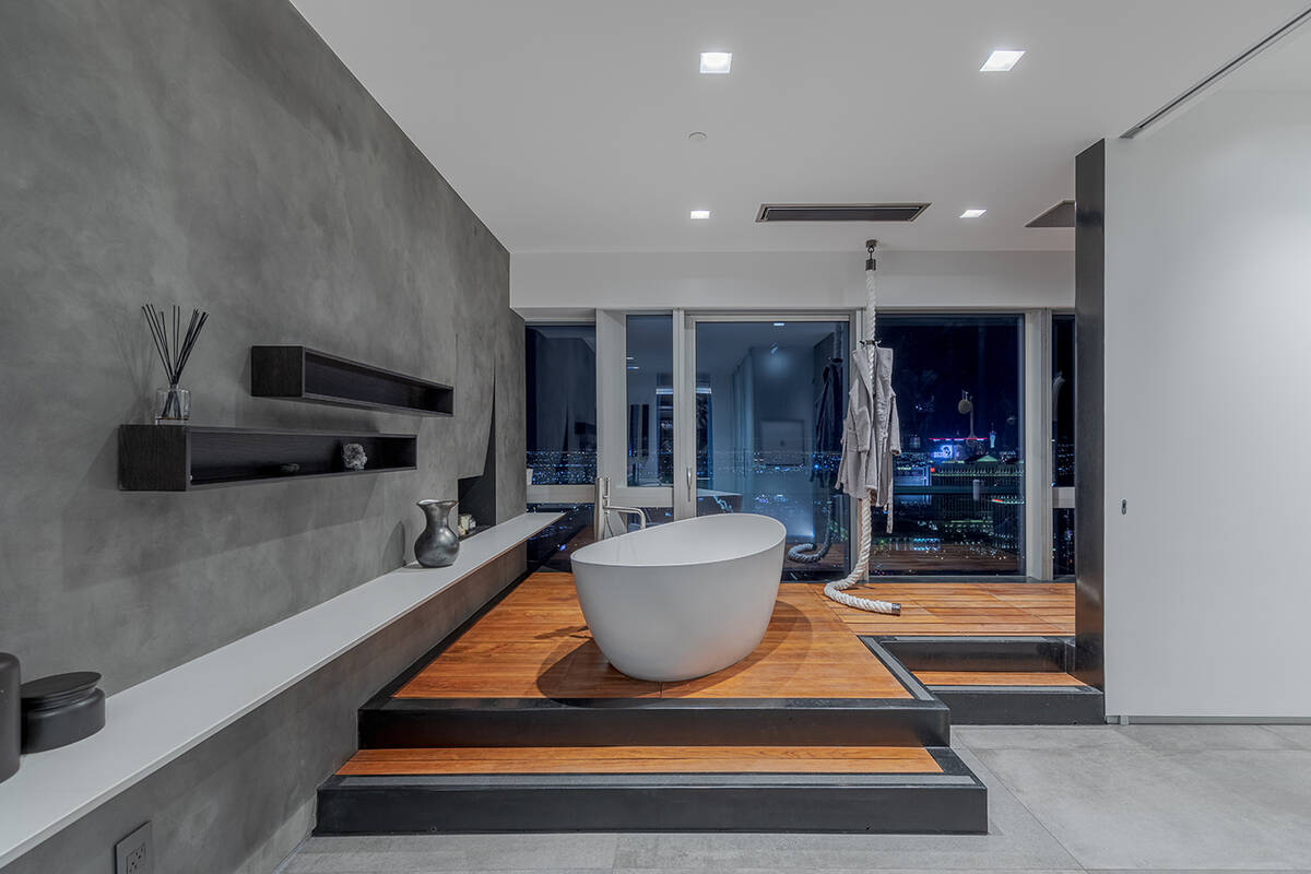 The master bath has floating teak vanity with dual sinks, raised soaking tub on teak flooring a ...