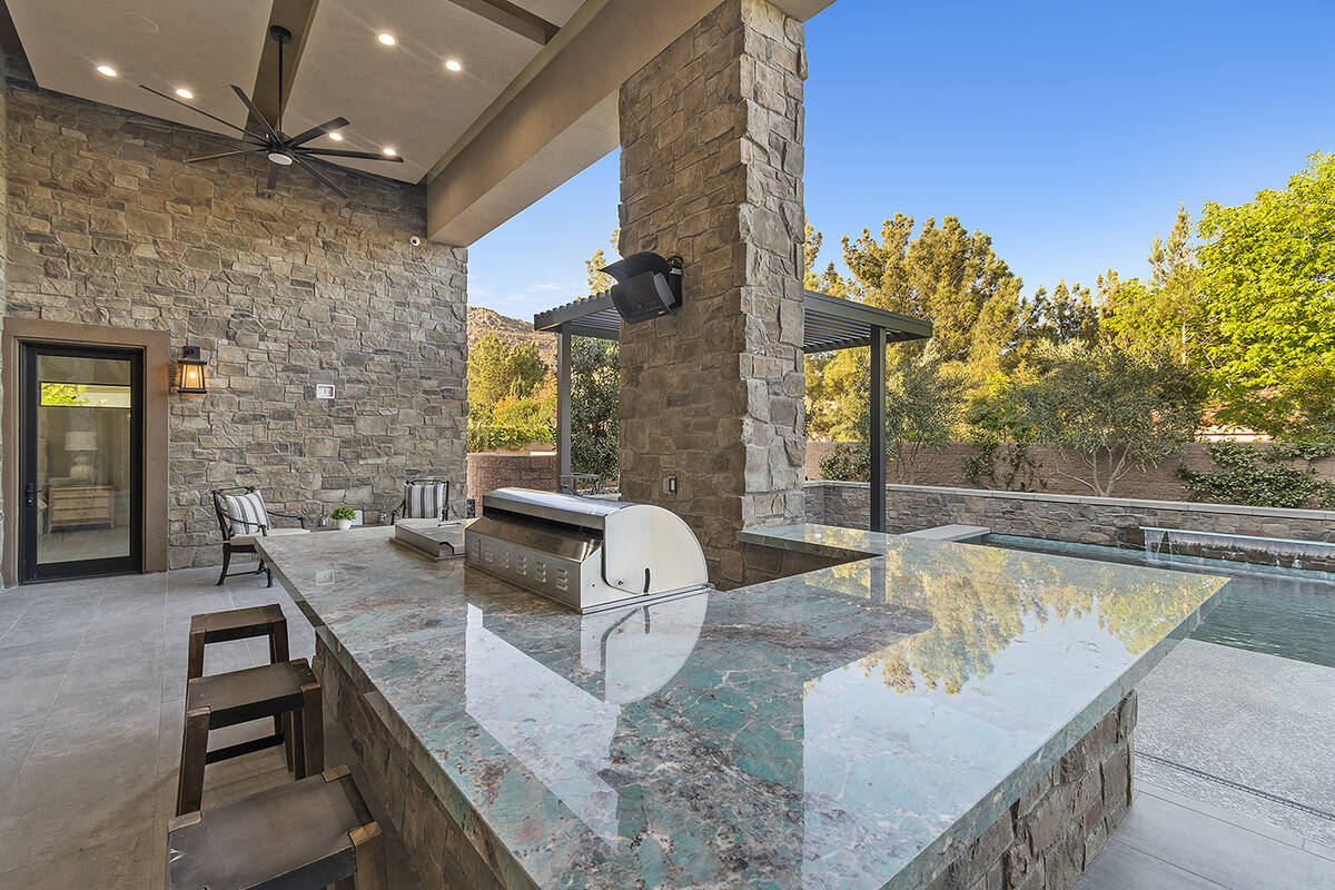 The expansive outdoor barbecue island, under a large, covered patio is highlighted by striking ...