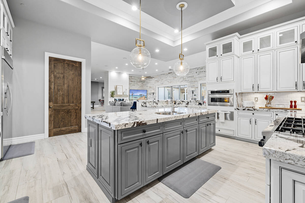 The kitchen features dual ovens, a built-in warming drawer and a wraparound island with extensi ...