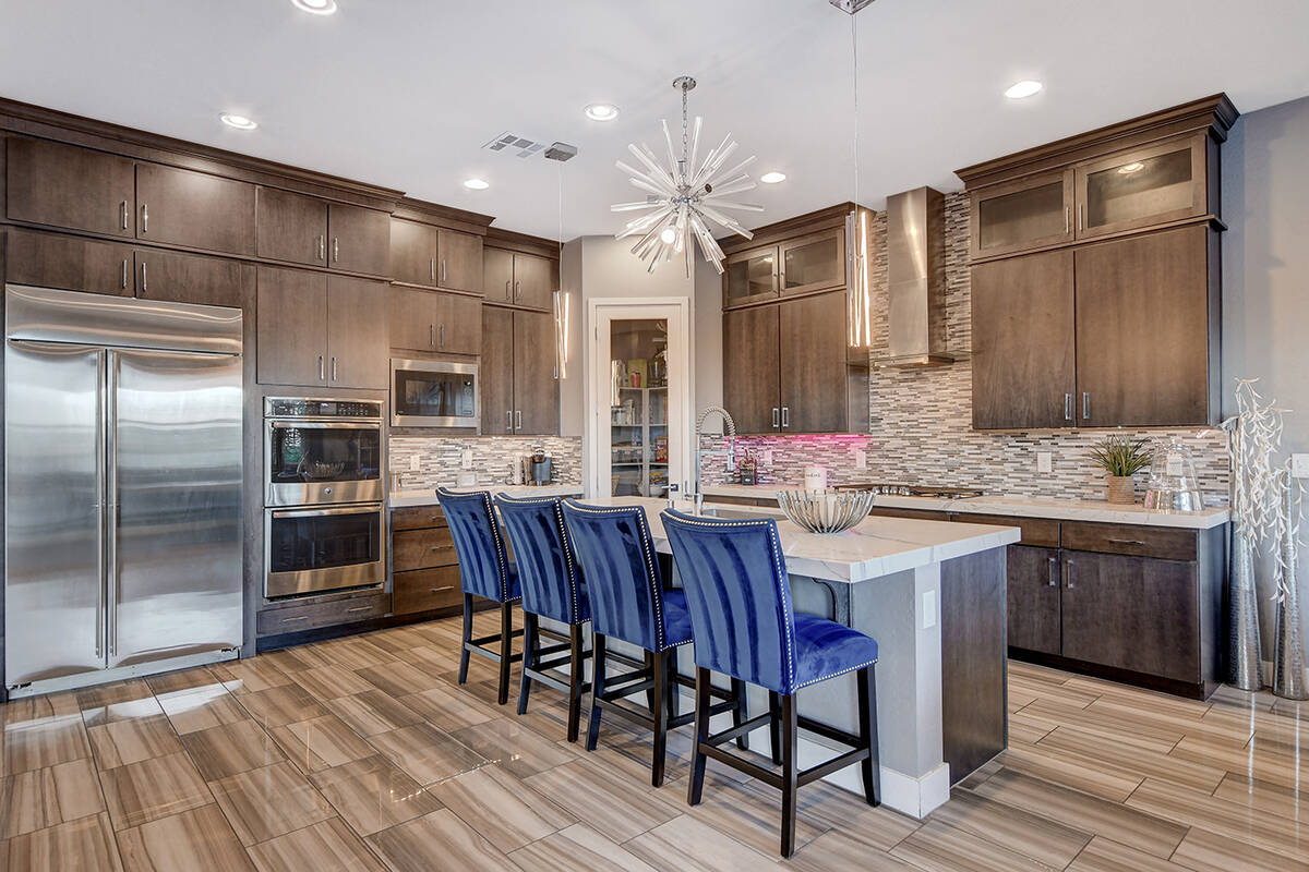 The kitchen features an island with seating, custom wood cabinetry, quartz countertops and prof ...