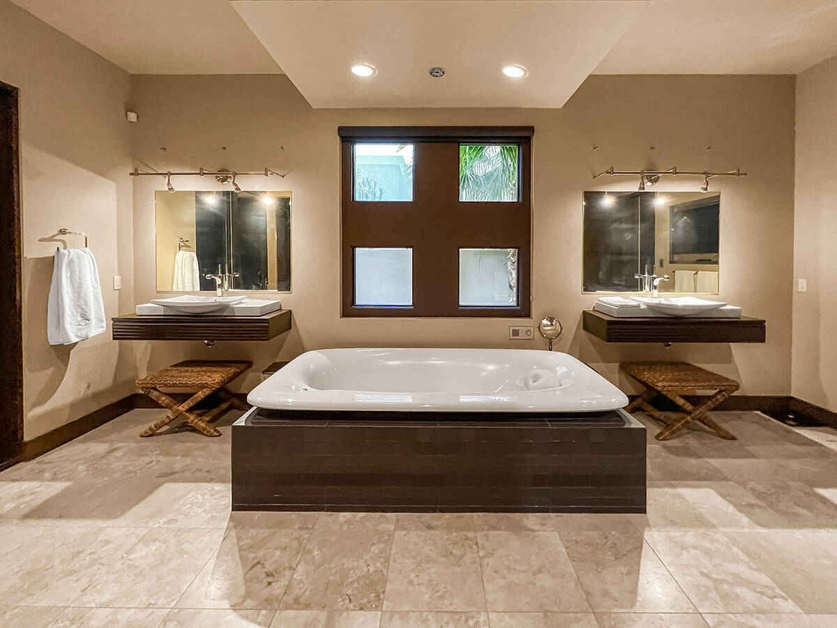 The master bath features double vanities, a soaking tub with water falling from the ceiling, an ...