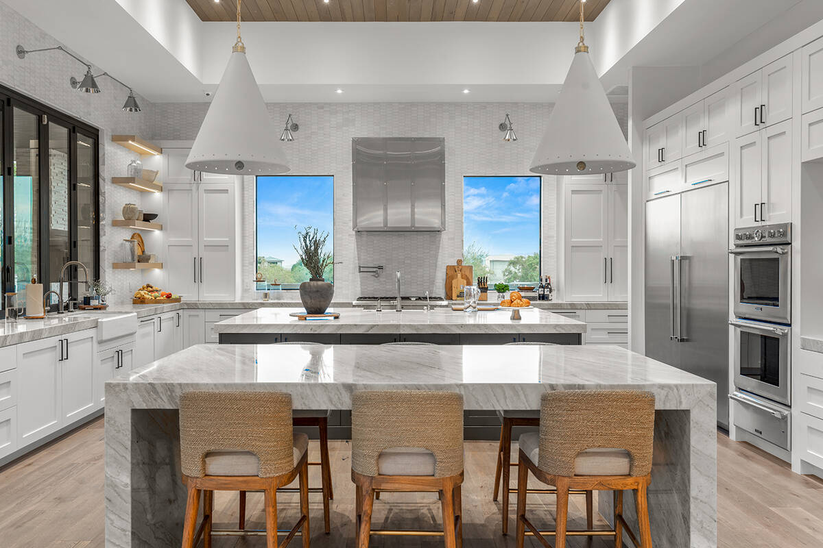 The one-story Summerlin home features a a chef’s kitchen with double islands and a marble bac ...