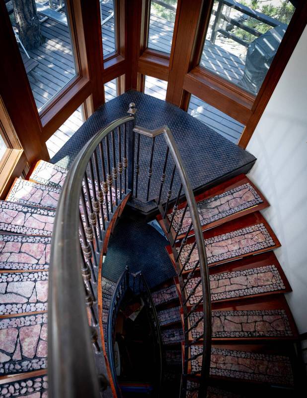 A custom curved floating staircase with an iron railing and hardwood steps greets guests upon e ...