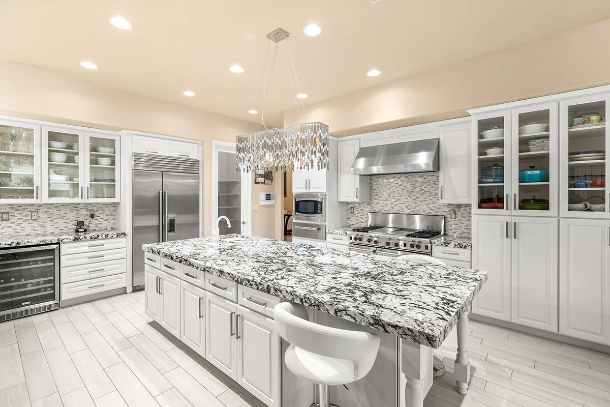 The renovated kitchen showcases white cabinets with a stone backsplash, an extended granite kit ...