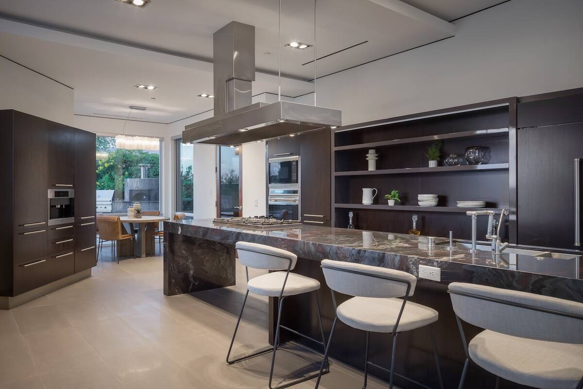 The kitchen features modern sleek lines with warm tones. It also has a large island with seatin ...