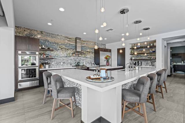 The kitchen has a square island with seating, lighting and upgraded appliances. (Real Broker LLC)