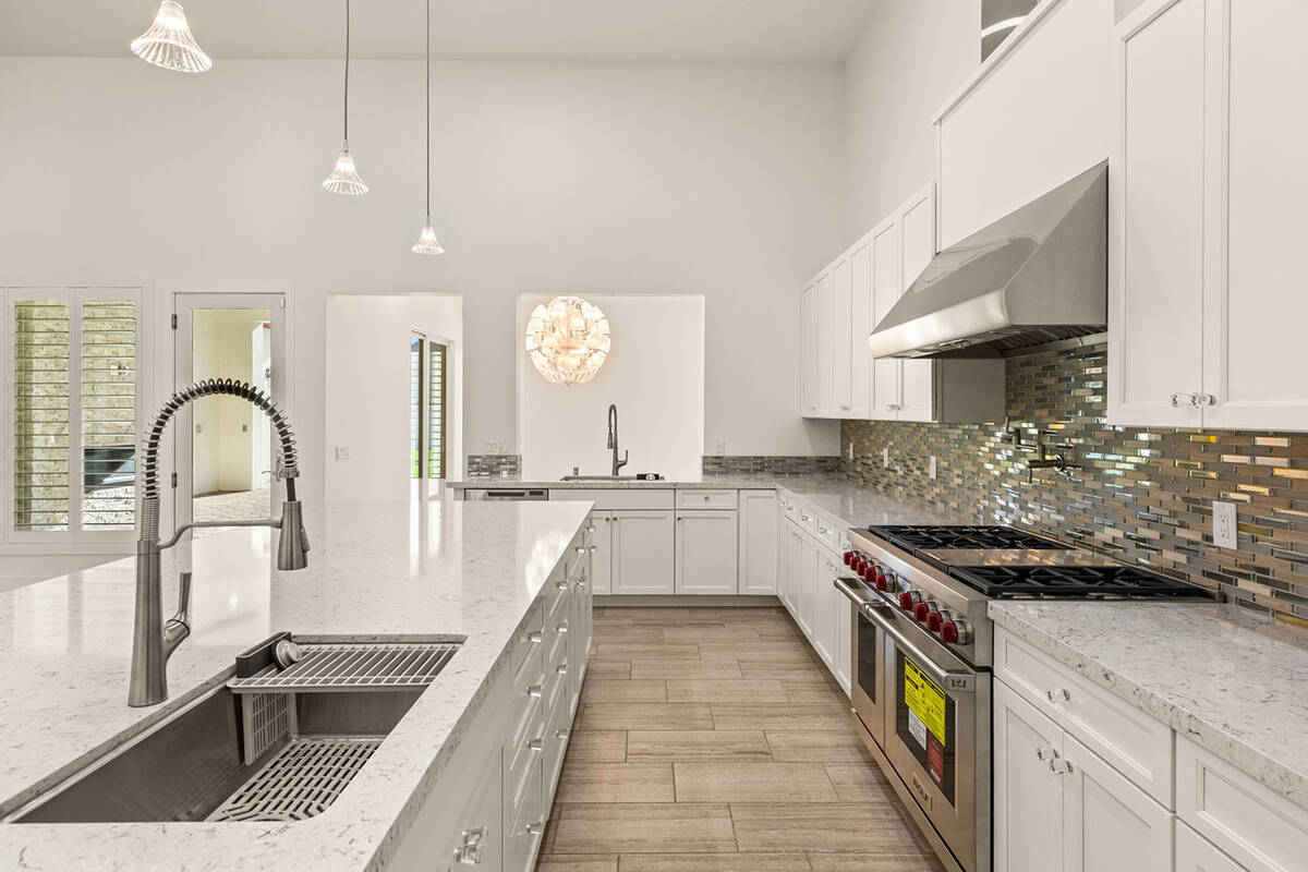 The kitchen features state-of-the-art wine fridge, large island with quartz countertops, vegeta ...