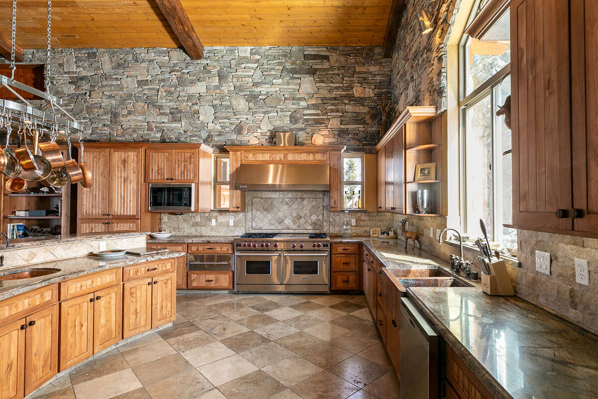 The spacious kitchen is complete with a professional-grade Wolf six-burner stove, custom alder ...