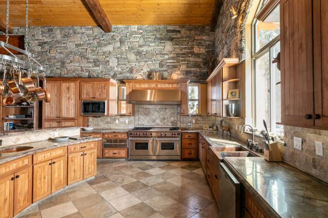 The spacious kitchen is complete with a professional-grade Wolf six-burner stove, custom alder ...