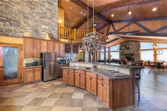 A curved island graced with granite counters and seating separates the kitchen from the main li ...