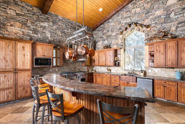 The spacious kitchen is complete with a professional-grade Wolf six-burner stove, custom alder ...