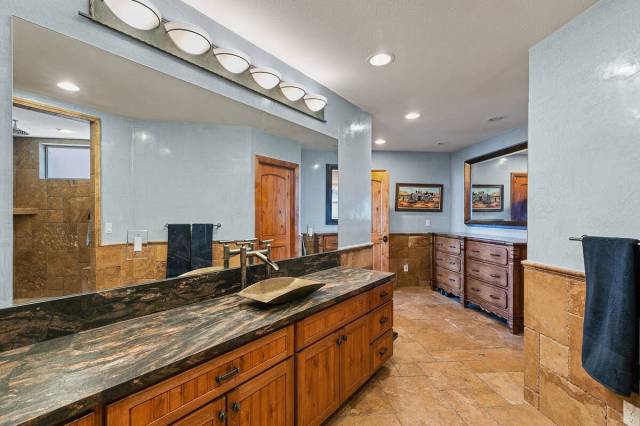 The primary spa-like bath features a voluminous walk-in shower with a stone surround, Venetian ...