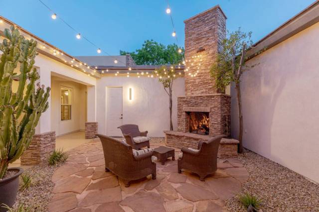 The outdoor wood-burning stone fireplace and comfy seating provide a warm, inviting ambiance. ( ...