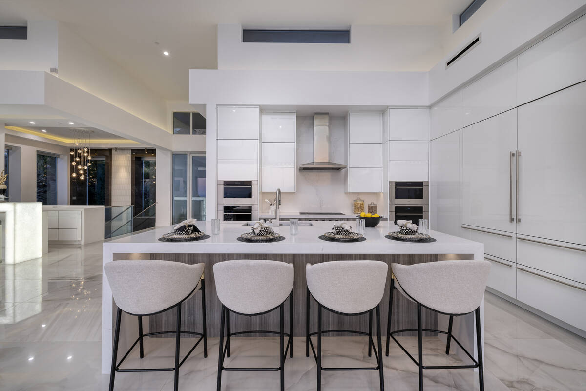 The kitchen has a large island with seating. Large-format porcelain tile flows throughout the m ...