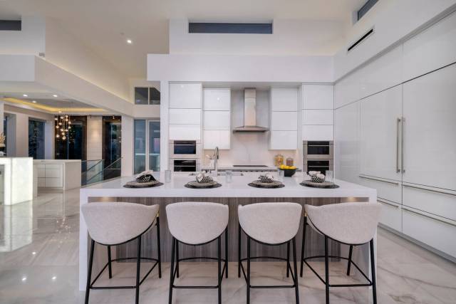 The kitchen has a large island with seating. Large-format porcelain tile flows throughout the m ...